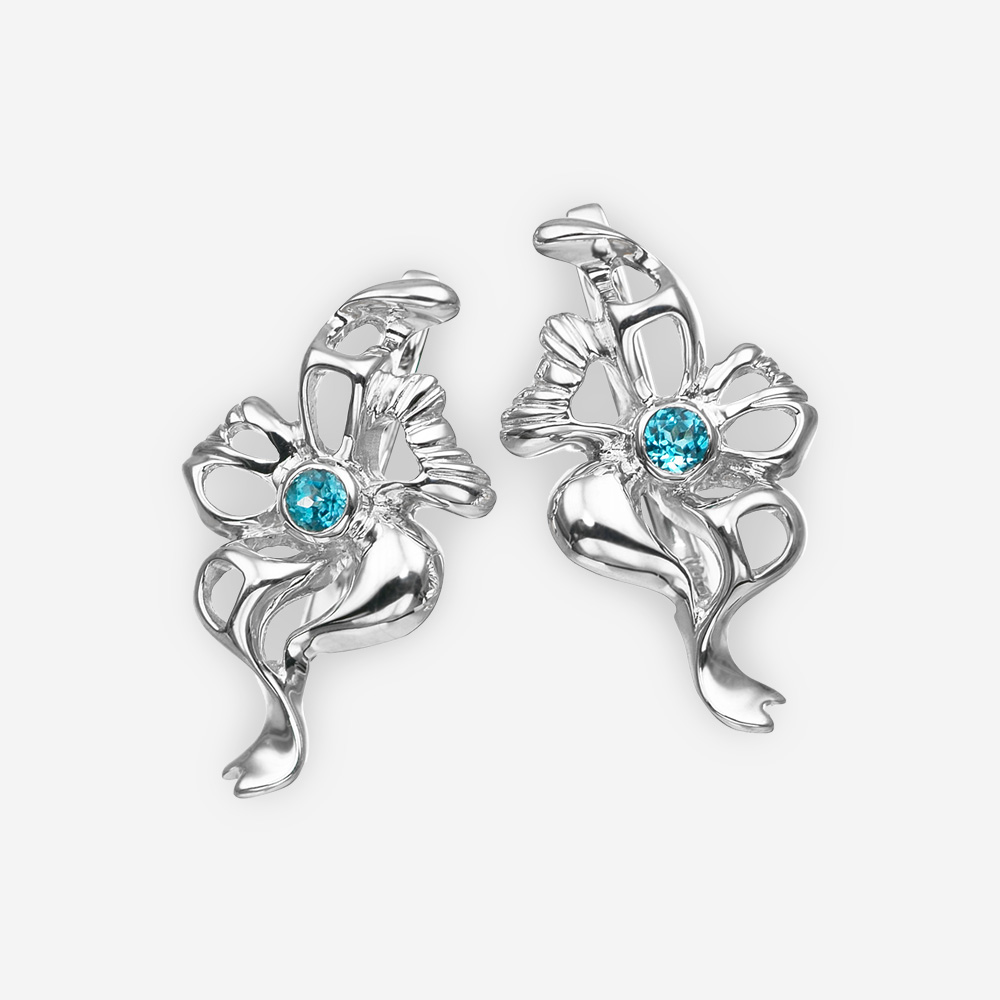 Aretes de plata en forma de flor con topacio azul y detalles a cielo abierto.